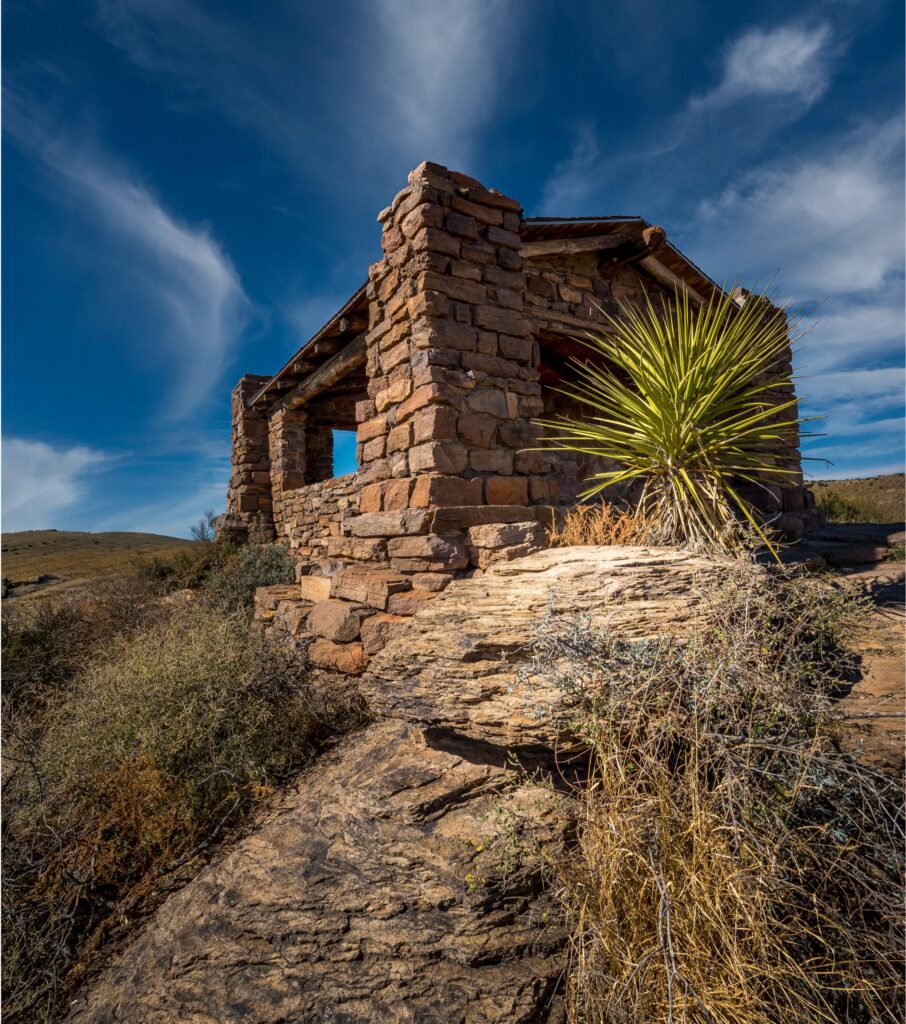 Blue skys with large rock leading up to a old rock bulding.