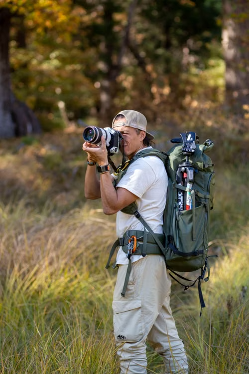 Backpacker using a DSLR camera to photograph nature in an autumn setting
